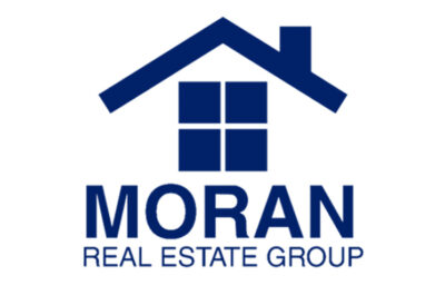 Moran Real Estate Group – 2026 Art Fest Sponsor Moran Real Estate Group logo featuring a blue house icon